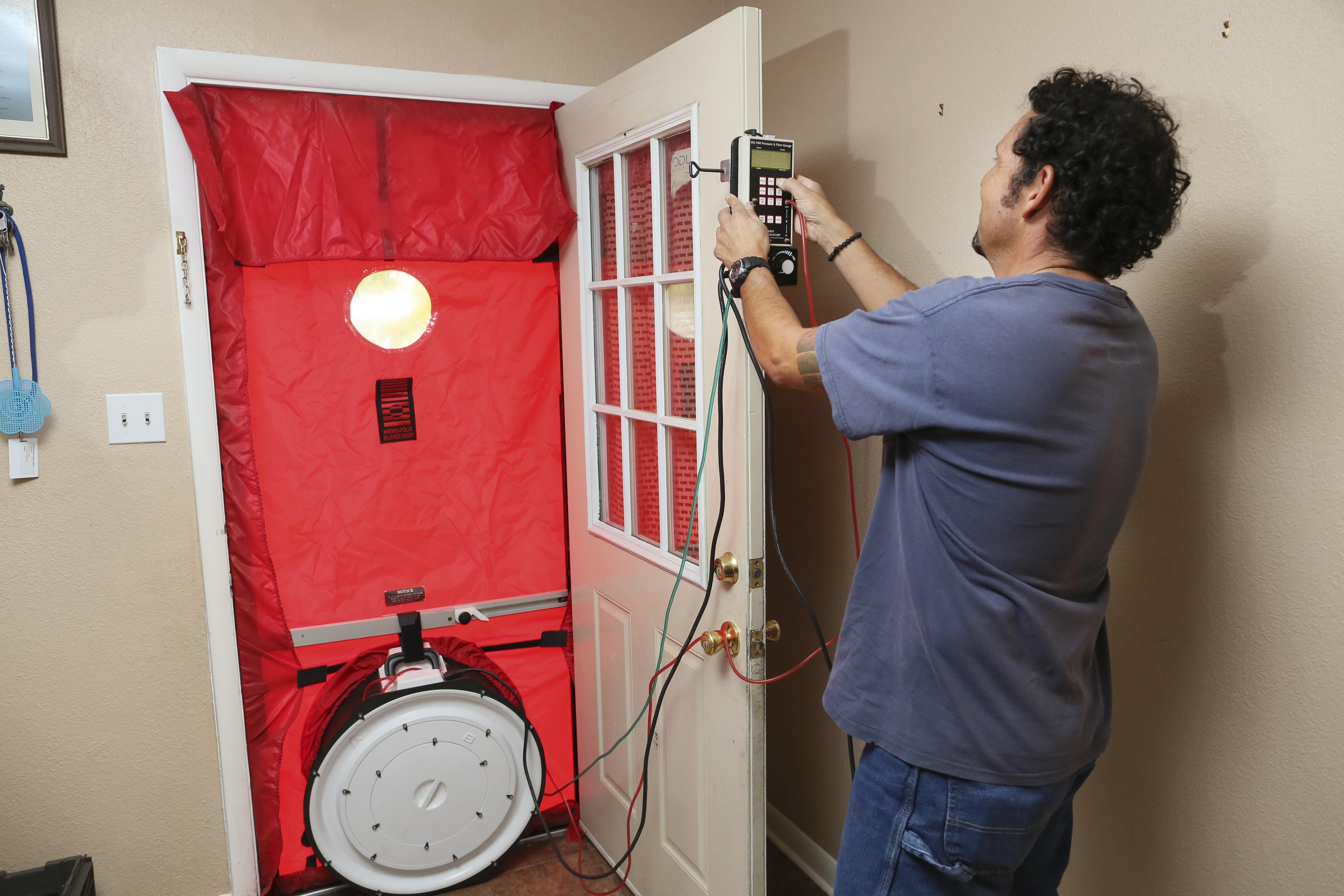 A man conducts a blower door test to test for air leaks at a home.