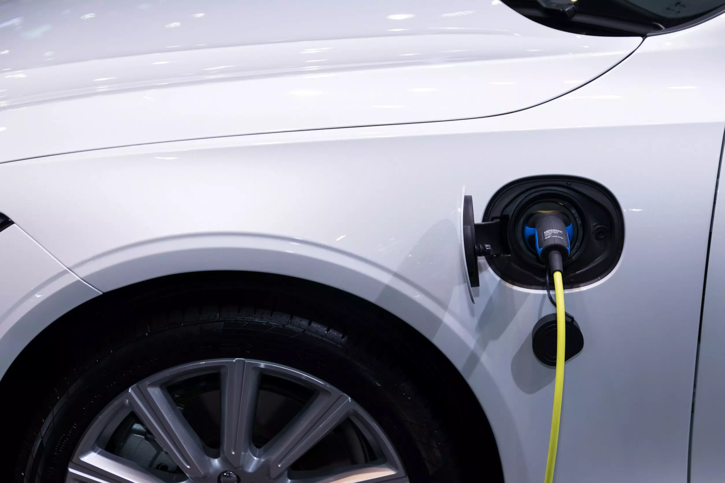 A close-up of an electric vehicle's charging port plugged in to charge.