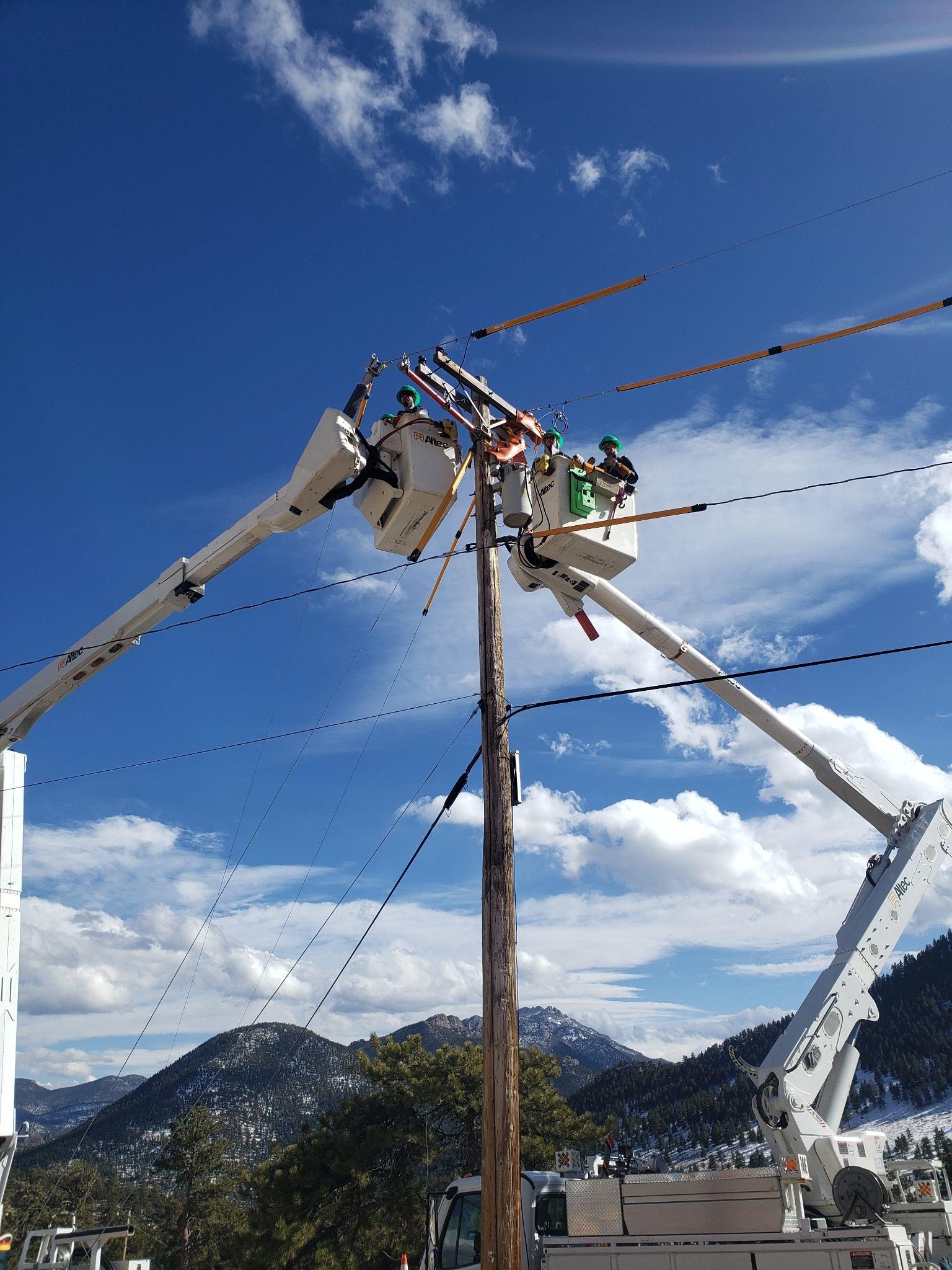 Estes Park lineworkers with mountain in the background