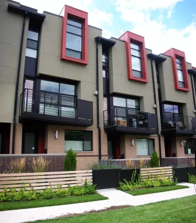 tan modern affordable housing townhomes shown with balconies and green landscaping