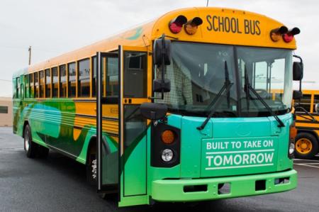 yellow electric schoolbus with green banner that reads "built to take on tomorrow"
