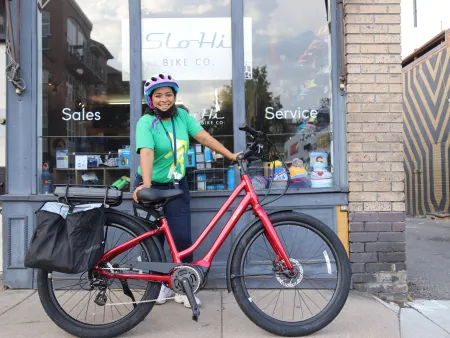 eBike program partcipant posting with her new eBike in front of a bike shop